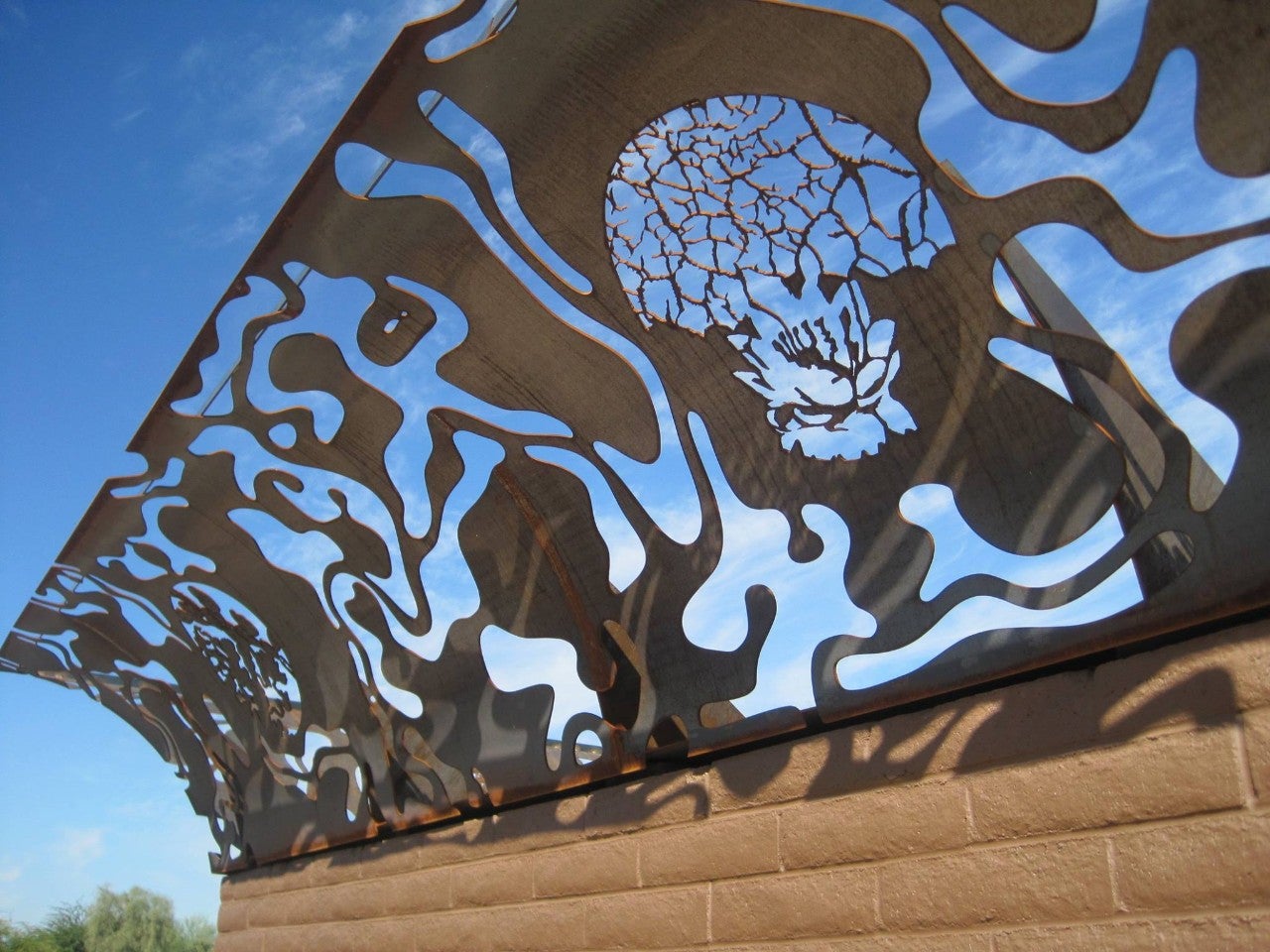 Metal sculpture with cutouts that contrast with the sky in the background.