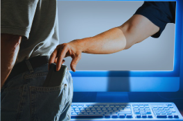 A computer monitor and keyboard are shown in the image. In front of the computer, a man is standing and appears to be walking away. His back, part of his arm, waist, and legs are visible. Inside the monitor, a thief’s arm reaches out from the screen and grabs the man's wallet from his back left pocket. The image symbolizes the dangers of cybercrime and identity theft.